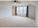 A bright bedroom featuring neutral carpeting, ceiling fan, and a large window at 9009 Powder Works Dr, Huntersville, NC 28078