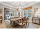 Bright dining room with a wooden table, chandelier, and access to a sunroom with a pool view at 1101 Churchill Downs Dr, Waxhaw, NC 28173