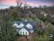 Twilight aerial view of the house, showcasing its roofline, surrounding trees, and beautifully lit windows at 1136 Bolling Rd, Charlotte, NC 28207