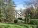 View of the home's exterior surrounded by mature trees, lush landscaping, and a brick patio at 1136 Bolling Rd, Charlotte, NC 28207