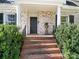 Close-up of the inviting brick steps and black door entrance to a white brick home at 1136 Bolling Rd, Charlotte, NC 28207