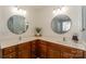 Well-lit bathroom features dual sinks, wood cabinets, and round mirrors creating a clean and functional space at 265 Sutro Forest Nw Dr, Concord, NC 28027