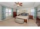 Spacious main bedroom featuring a tray ceiling, ceiling fan, and large windows with curtains at 265 Sutro Forest Nw Dr, Concord, NC 28027