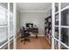 Home office with hardwood floors, a desk, chair, and built-in shelves, accessible through double doors at 265 Sutro Forest Nw Dr, Concord, NC 28027