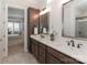 Bathroom featuring double vanity with framed mirrors, modern lighting, and view into main bedroom at 6248 Raven Rock Dr, Denver, NC 28037