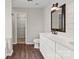 Bright bathroom features a double sink vanity with white cabinets, framed mirror, and wood-look flooring at 888 Brevard Place Rd, Iron Station, NC 28080