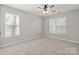 This bedroom features neutral carpet, two windows, and ceiling fan at 888 Brevard Place Rd, Iron Station, NC 28080