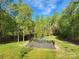 A scenic view of a backyard with a pool and wooden deck surrounded by lush trees at 888 Brevard Place Rd, Iron Station, NC 28080