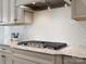 Close-up of kitchen featuring granite counters, stylish backsplash and stainless gas cooktop at 120 Trelawn St, Fort Mill, SC 29715