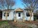 Inviting home with a charming stone-accented porch, new gray siding, and a manicured lawn at 13655 Broadway Ave, Midland, NC 28107