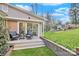 Back patio with two chairs and a table, a brick garden bed, and lush green grass at 3828 Chandworth Rd, Charlotte, NC 28210