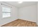 Bedroom with hardwood floors, one window, and white walls creating a bright, neutral space at 3828 Chandworth Rd, Charlotte, NC 28210