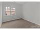 Well-lit bedroom featuring carpeted floor and a window at 7620 Rolling Meadows Ln, Huntersville, NC 28078