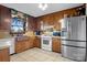 Charming kitchen with stainless steel refrigerator, tile floors, wooden cabinets and view of the backyard at 1262 Ring Tail Rd, Claremont, NC 28610