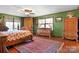 This large main bedroom features a red rug, green walls, and unique wooden furniture at 1262 Ring Tail Rd, Claremont, NC 28610