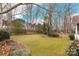 A view of the backyard with mature trees, a grassy lawn, and partial stone retaining walls at 17521 Cambridge Grove Dr, Huntersville, NC 28078