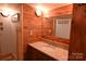 Wood-paneled bathroom featuring a mirror, granite-topped vanity, decorative lights, and modern fixtures at 198 Clouse Ln, Taylorsville, NC 28681