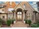 Beautiful brick home entrance with an arched doorway, stone accents, and decorative landscaping at 2907 Cutter Ct, Waxhaw, NC 28173