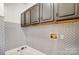 Laundry room with gray cabinets and patterned backsplash at 9236 Silver Pine Dr, Charlotte, NC 28277