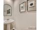 Powder room with pedestal sink, arched mirror, and decorative artwork at 117 Mountain Bridge Way, Statesville, NC 28625