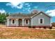 Ranch style home with light blue siding, covered porch, and a grassy yard at 5704 Bentgrass Ct, Monroe, NC 28110