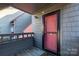 Inviting condo entrance with a vibrant red door, gray siding, and cozy outdoor area at 9037 J M Keynes Dr # 23, Charlotte, NC 28262