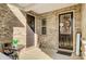 Inviting front porch featuring dual entry doors, brick walls, and a cozy seating area at 9428 Liberty Hill Dr, Mint Hill, NC 28227