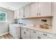 Bright laundry room features white cabinets, countertop space, front load washer and dryer, and a window at 128 Ballantree Rd # 46, Mooresville, NC 28115