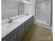 Double vanity bathroom with gray cabinets and frameless shower at 2124 Electric Ln, Charlotte, NC 28205