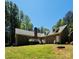 Rear view of a brick home with a deck, a fireplace chimney, and surrounded by trees at 395 Paulownia Dr, China Grove, NC 28023