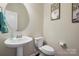Stylish powder room featuring a pedestal sink, round mirror, and neutral wall color at 857 Spelman Dr, Indian Land, SC 29707