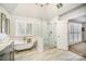 Bright bathroom featuring soaking tub, glass enclosed shower, and large window with white shutters at 10111 Grimsby Ct, Huntersville, NC 28078