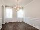 Formal dining room featuring hardwood floors, elegant chandelier, and white wainscoting at 127 Doncaster Dr, Mooresville, NC 28115