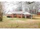 View of red brick house with white trim, metal roof, carport and spacious grassy yard at 1715 Emmanuel Church Rd, Conover, NC 28613