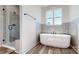 Modern bathroom showcasing a separate shower and tub, enhanced by wood-look flooring and grey tiled walls at 2906 Lathan Rd, Monroe, NC 28112