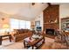 Cozy living room featuring a brick fireplace, ceiling fan, and comfortable brown sofa at 5701 Glenshire Ct, Charlotte, NC 28269