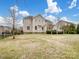 Large backyard with grass, tree line and neutral-toned two-story home at 8509 Penton Pl, Harrisburg, NC 28075