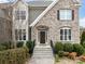 Close up of the home's exterior shows an inviting stone facade and classic dark wood front door at 8509 Penton Pl, Harrisburg, NC 28075