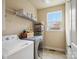 Well-equipped laundry room with front-load washer and dryer, wire shelving, and natural light, ideal for efficient laundry care at 8509 Penton Pl, Harrisburg, NC 28075