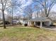 Exterior view featuring a well-maintained lawn, mature trees, and a convenient carport for parking at 1116 Circlewood Dr, Charlotte, NC 28211
