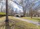 View of house and garage with mature trees, grass and a long driveway at 1116 Circlewood Dr, Charlotte, NC 28211