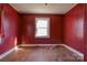 Room with hardwood flooring and blank red walls, showing a window with some materials on the floor at 2021 Willis Dr, Shelby, NC 28152