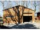 Single car garage with a gable roof featuring a partially opened door and an entrance to the side at 308 N Hawthorne St, Mount Holly, NC 28120