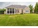 Backyard with sunroom, brick exterior, lush green grass, and a patio area perfect for outdoor entertaining at 3850 Hounslow Ln, Harrisburg, NC 28075
