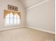Bedroom with vaulted ceiling, neutral carpet, and a window with plantation shutters at 3850 Hounslow Ln, Harrisburg, NC 28075