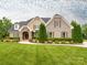 Charming brick home featuring a stone entryway, lush landscaping, and a well-manicured lawn at 3850 Hounslow Ln, Harrisburg, NC 28075