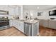 Modern kitchen boasts white cabinets, stainless steel appliances, and an island with granite countertop, seamlessly flowing into the living area at 9142 Mackinaw Dr, Gastonia, NC 28056