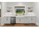 Clean white kitchen with farmhouse sink, floating shelves, and stainless steel appliances at 114 Quail Ridge Dr, Mooresville, NC 28117