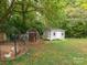 Backyard with two storage sheds and a chicken coop surrounded by lots of trees at 1204 Allenbrook Dr, Charlotte, NC 28208