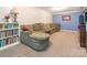 Basement features a large sectional couch, bookcase and carpeted flooring at 1204 Allenbrook Dr, Charlotte, NC 28208